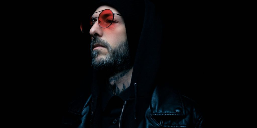 Portrait mélancolique d'un homme en veste de cuir noire et lunettes teintées rouges sur fond sombre