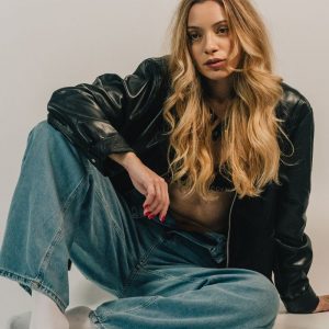 Fashion-forward woman sitting casually in denim and leather jacket