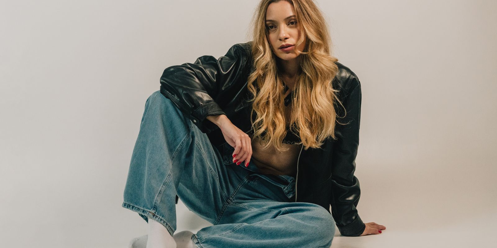 Buneri.fr | Veste en Cuir ou Veste en Jean : Laquelle Choisir ? Fashion-forward woman sitting casually in denim and leather jacket