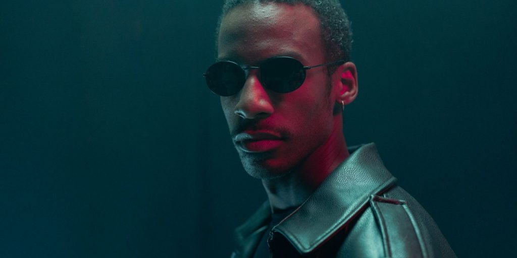 Portrait stylisé d'un homme en lunettes de soleil et veste en cuir dans une ambiance dramatique