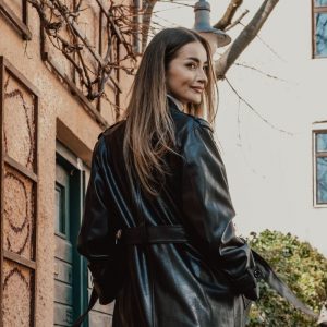 Femme elegante en long manteau de cuir noir marchant dans une rue couverte de graffitis