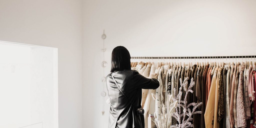 Une femme regarde des blousons en cuir sur un portant dans une boutique lumineuse et élégante